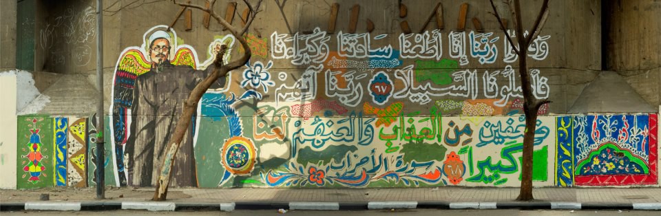 A 10-meter long mural on the AUC Library with the Revolution's sheikh, Al-Azhar Islamic scholar Emad Effat, shot dead during Cairo protests on 16 th December 2011 by the military police. The verses at center-stage read, "God, we obeyed our lords and they